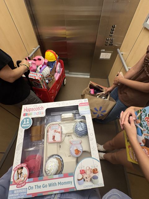 Volunteers in an elevator with a wagon and bags full of toys
